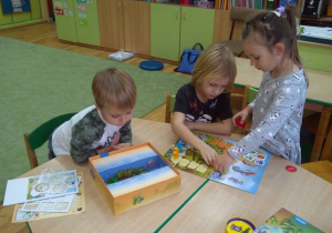 Troje dzieci gra w grę planszową "Smoki"